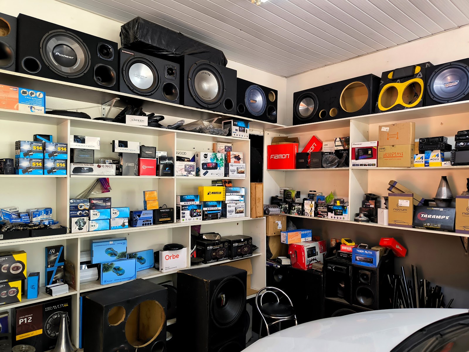 Prateleiras brancas da World Sound 1 cheias de subwoofers, alto-falantes e caixas de som