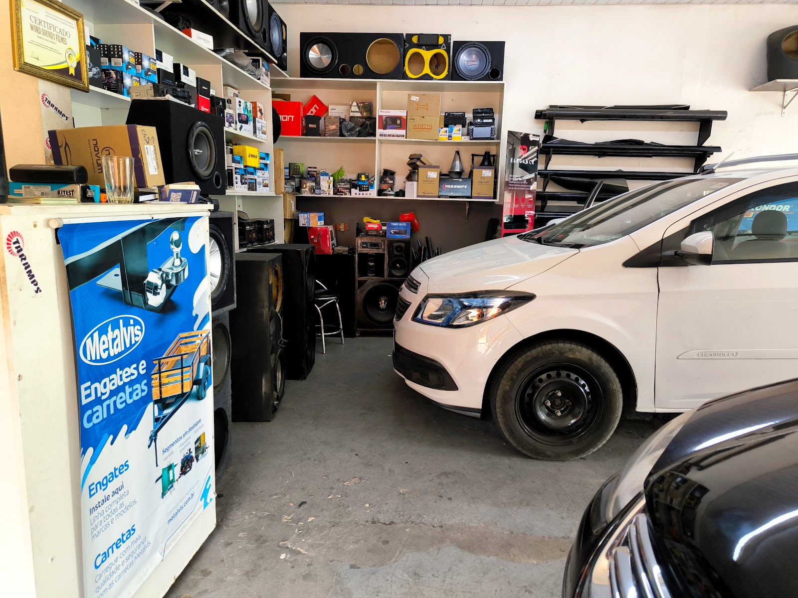 Interior da loja com banner de engates e carretas e dois carros em atendimento